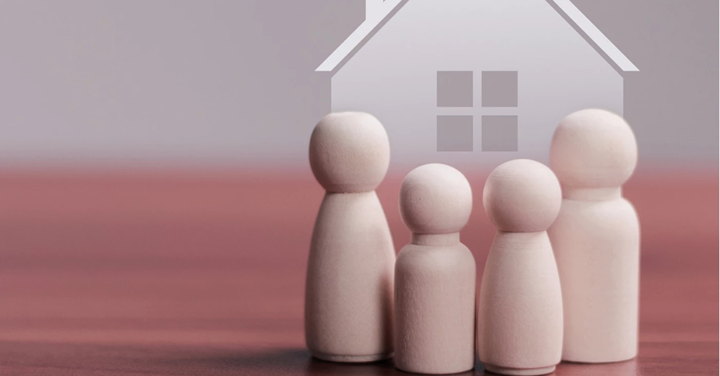 4 wooden pegs representing a family in front of an image of a house